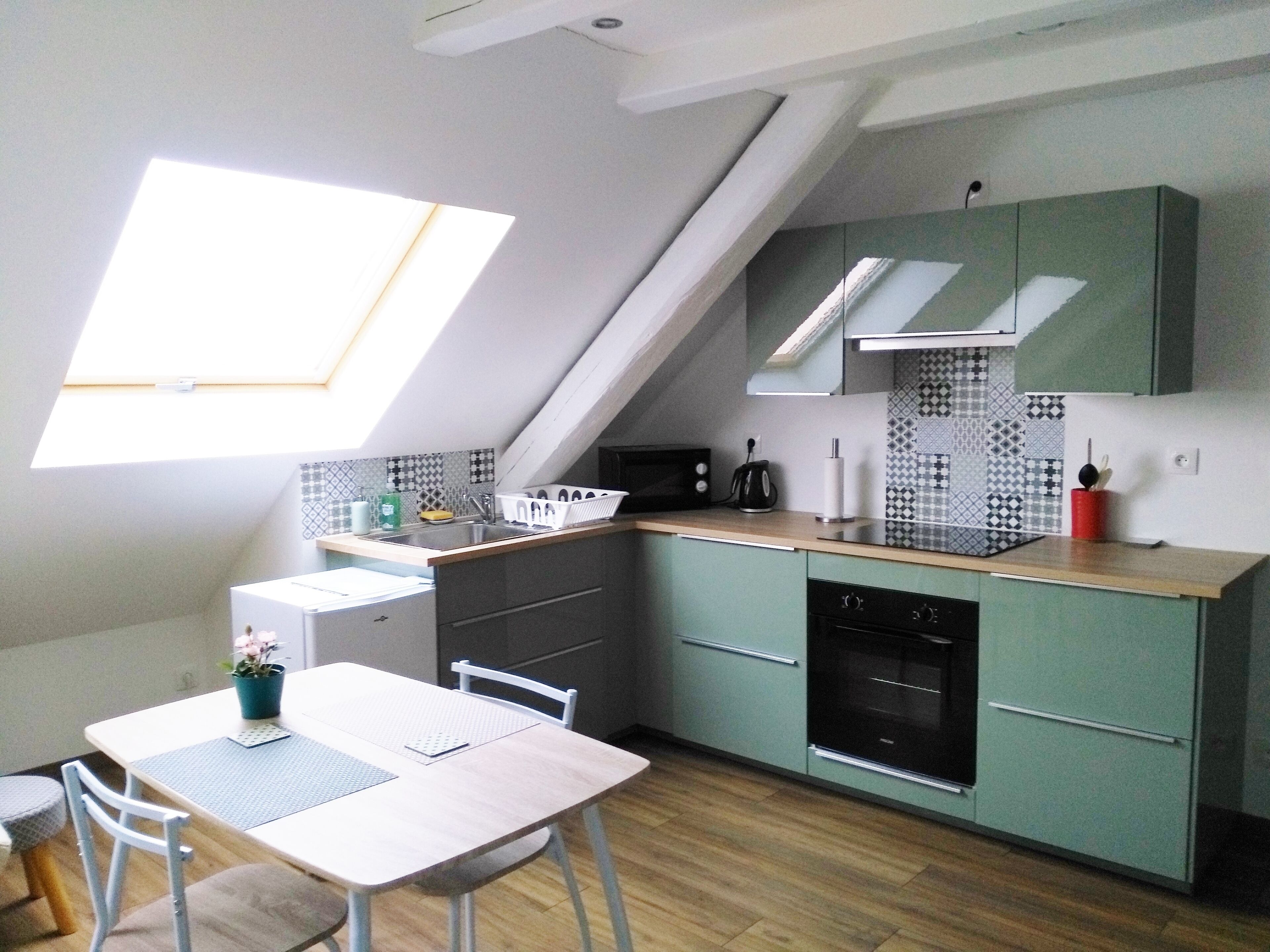A compact kitchen with a skylight, a dining area with a table and chairs, and a dishwasher.