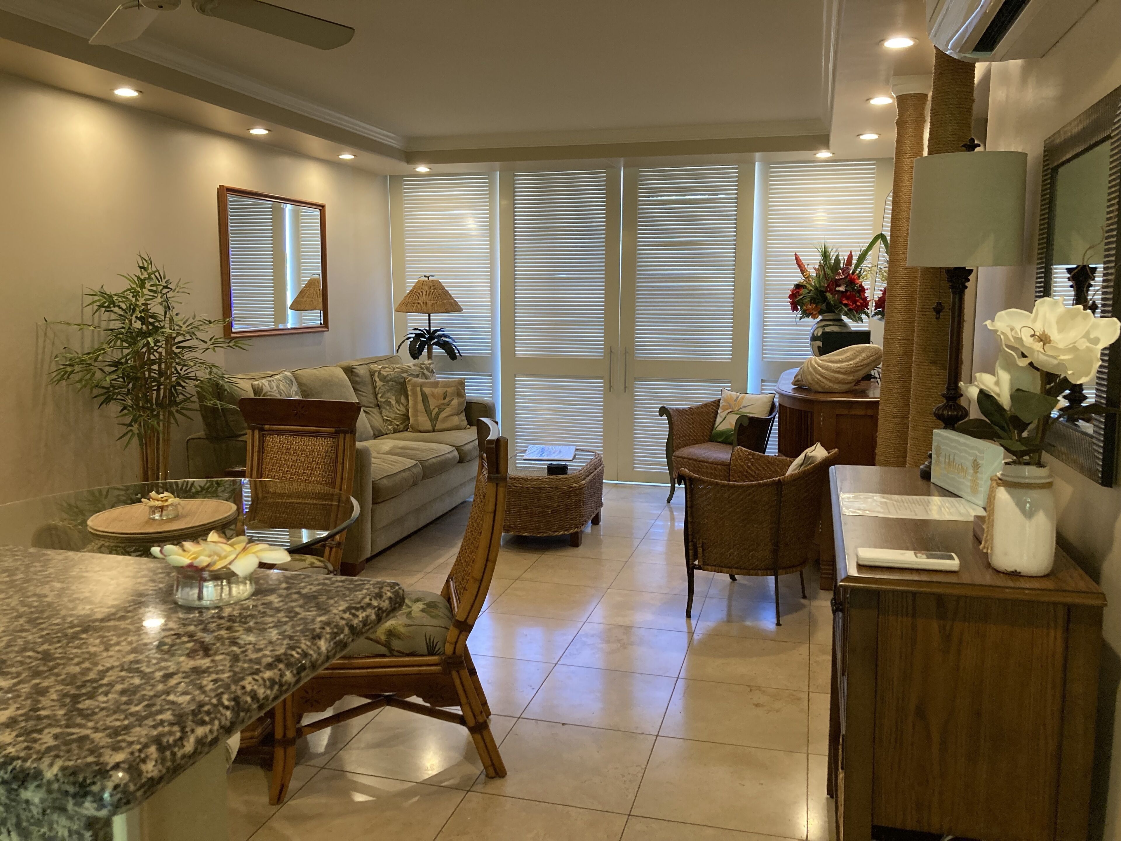 A modern living room with a sofa, armchairs, a dining table, and a kitchen area.