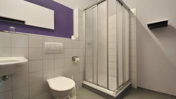 Un baño con inodoro, lavamanos y cabina de ducha de vidrio.