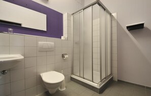 A bathroom with a toilet, sink, and a glass shower enclosure.