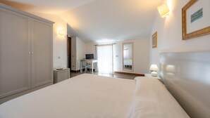 A hotel room with a large bed, a desk with a chair, a television, and a window with curtains. - Albergo Residenziale La Corte (Tortoli)