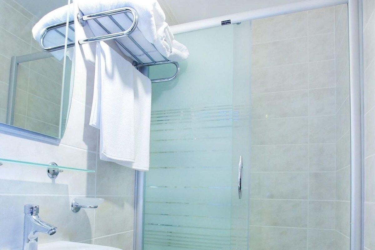 A bathroom with a glass-enclosed shower, a white sink, and a mirror.