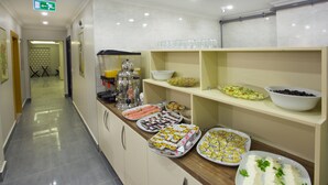 Passadís d'hotel amb zona de buffet que ofereix diferents aliments i un dispensador de suc.