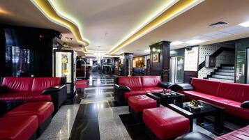 Eine Hotelhalle mit roten Ledersofas, einem Schachbrettmuster-Boden und einer Treppe.