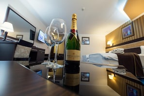 Una habitación de hotel con minibar, una cama, un televisor y una botella de Moët & Chandon Brut Imperial champagne.
