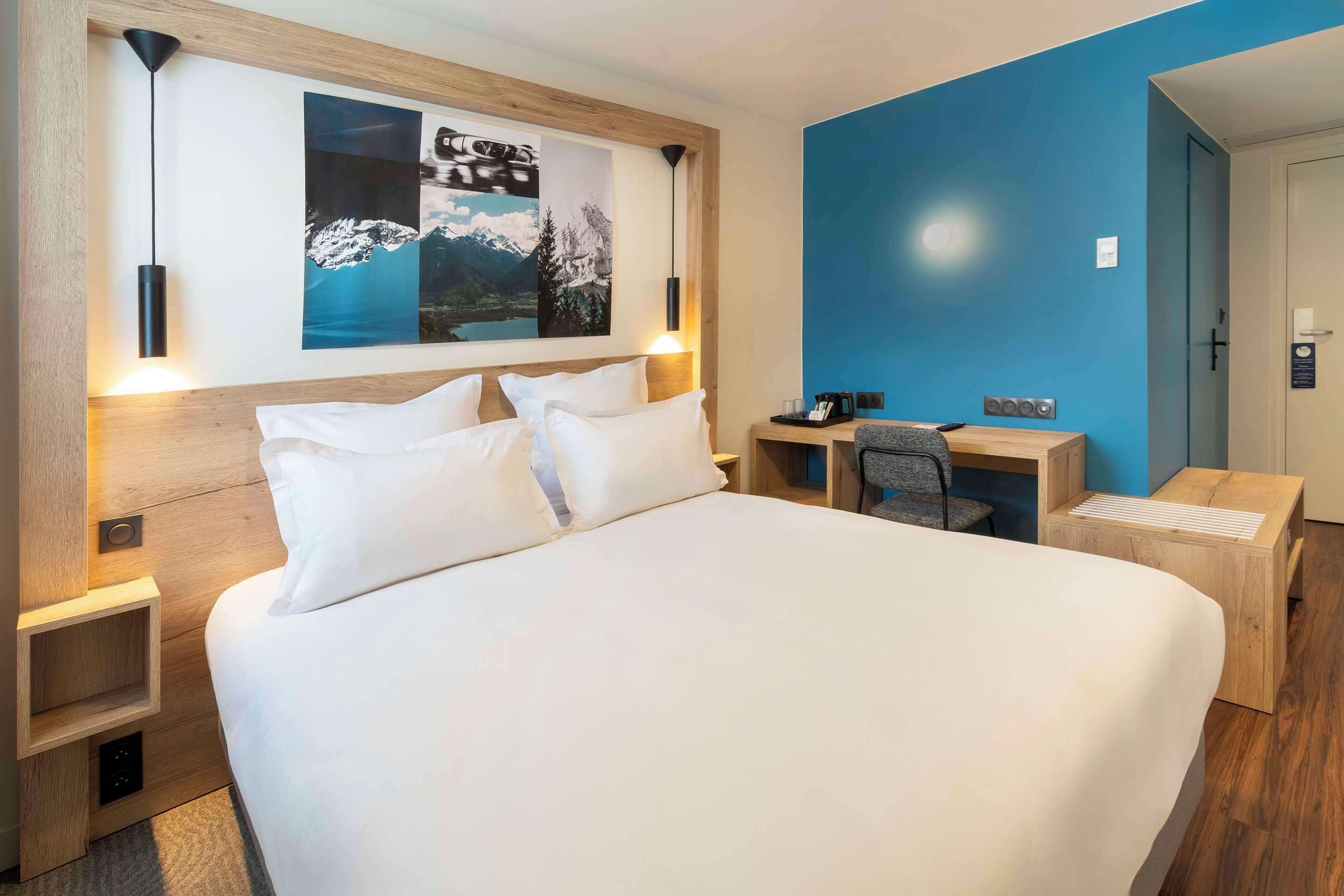 Une chambre d’hôtel moderne, dotée d’un grand lit, d’un bureau et d’une chaise.