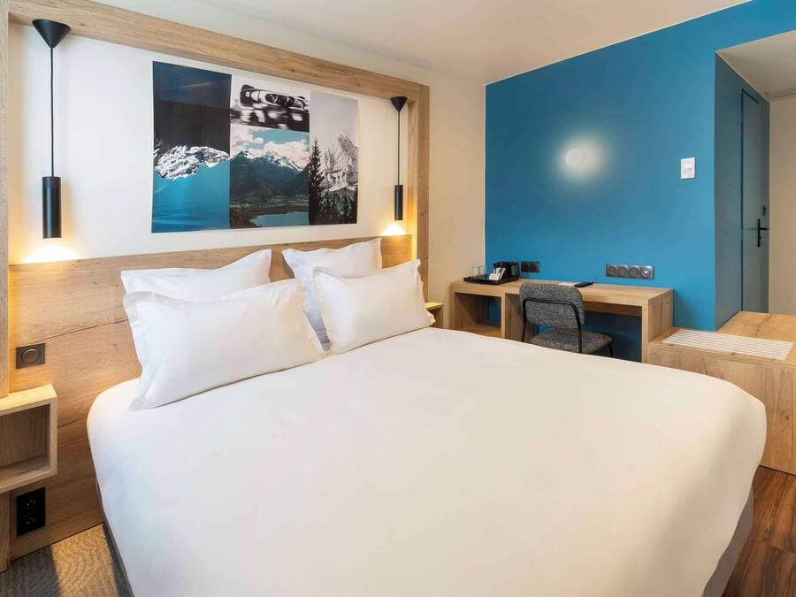 Une chambre d’hôtel moderne, dotée d’un grand lit, d’un bureau et d’une chaise.