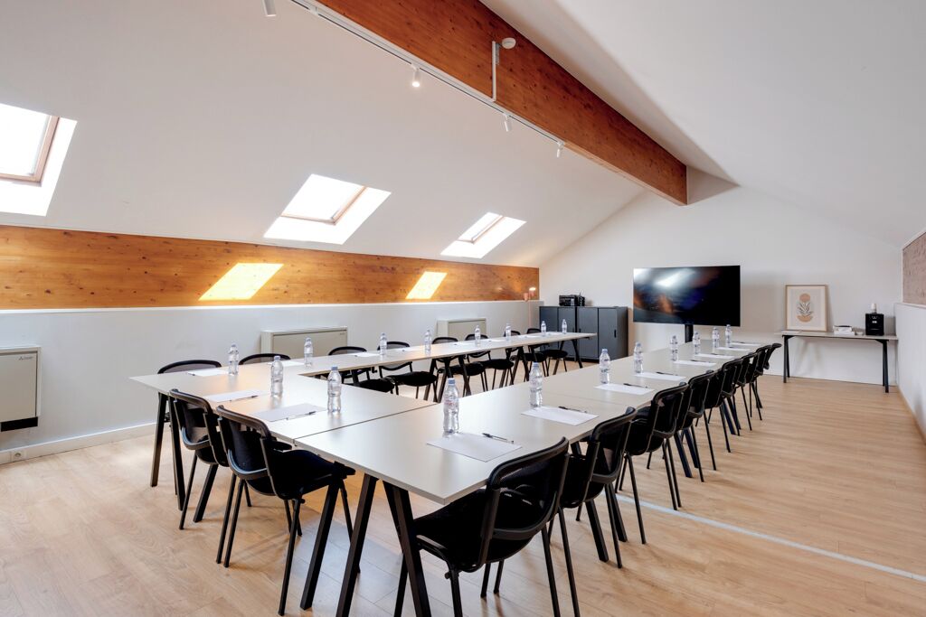 A conference room with a long table, black chairs, and a flat-screen TV.