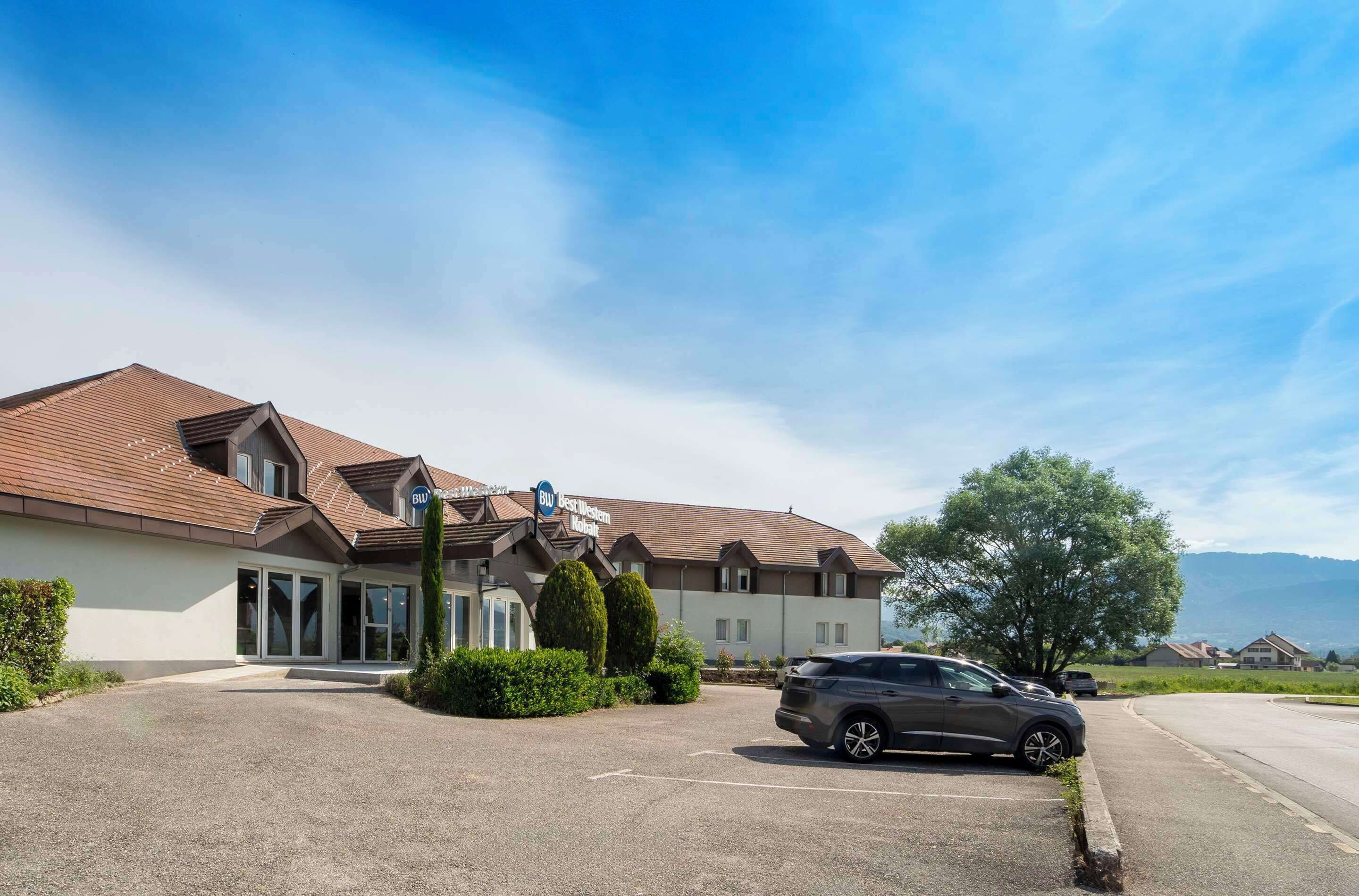 Ein Hotel mit modernem Design, inklusive Parkplatz und einem geparkten Auto davor.