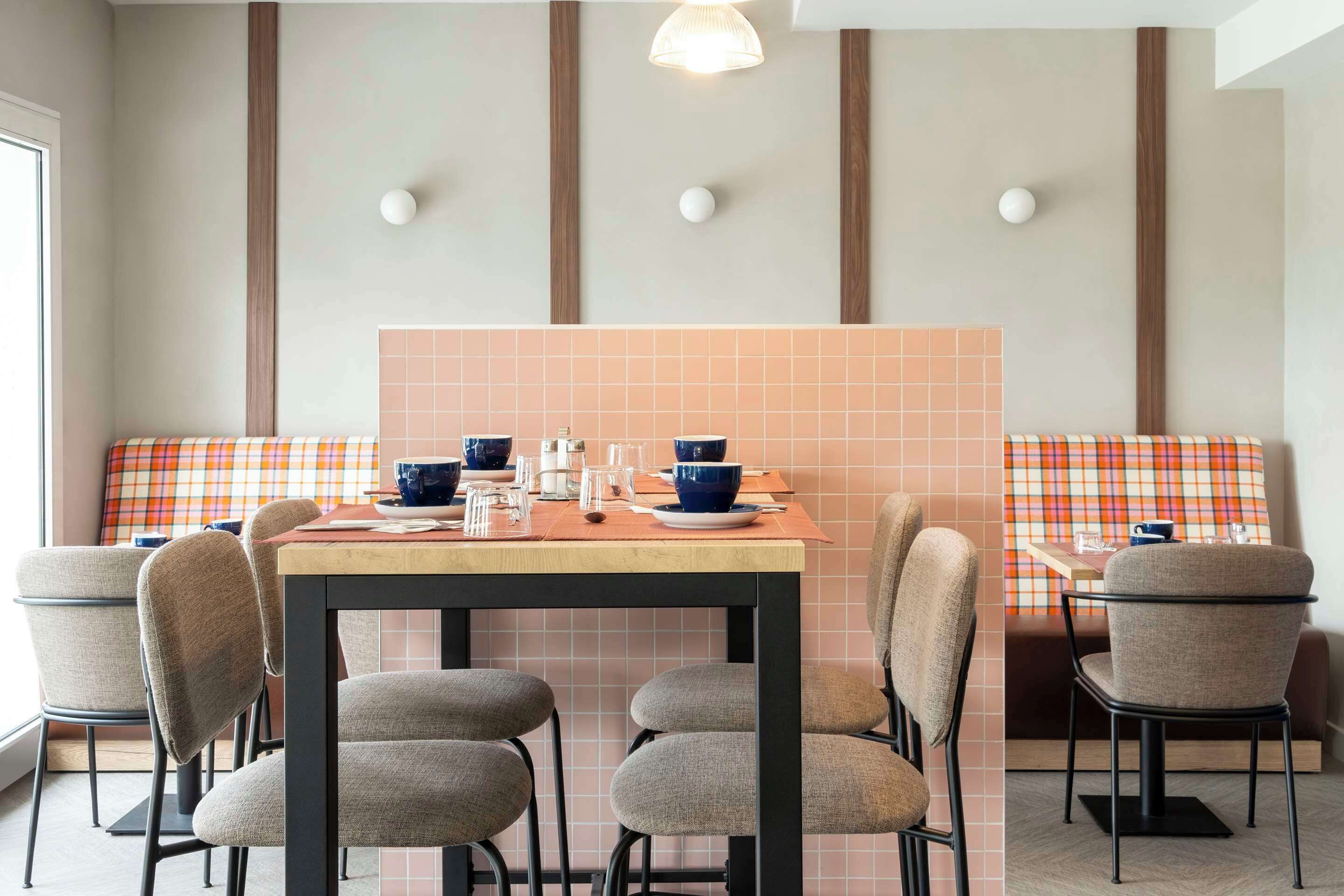 A dining area with a table set for four, surrounded by chairs, and a bench with a plaid cushion.