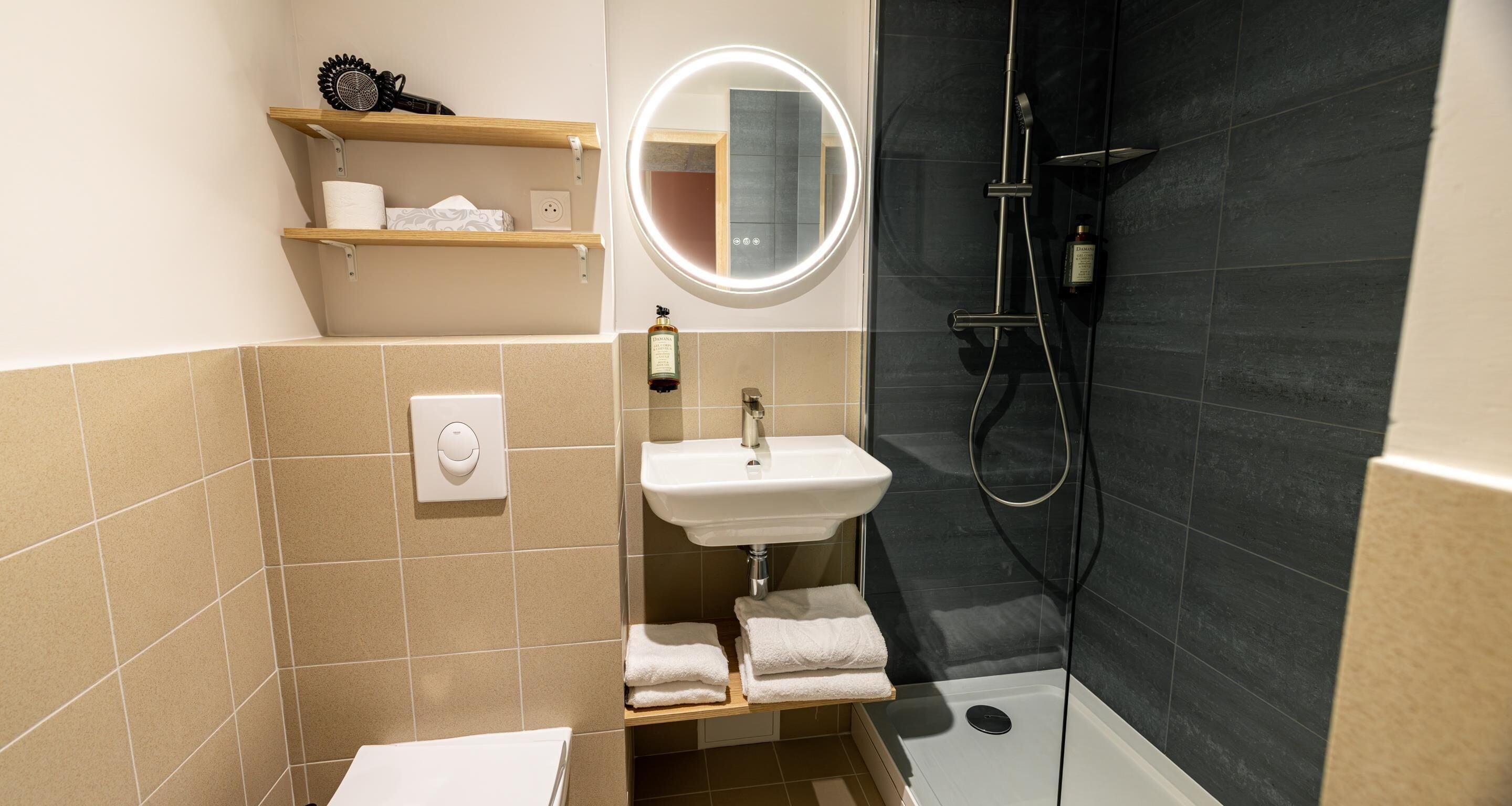Baño con lavamanos, espejo, toallero y ducha.