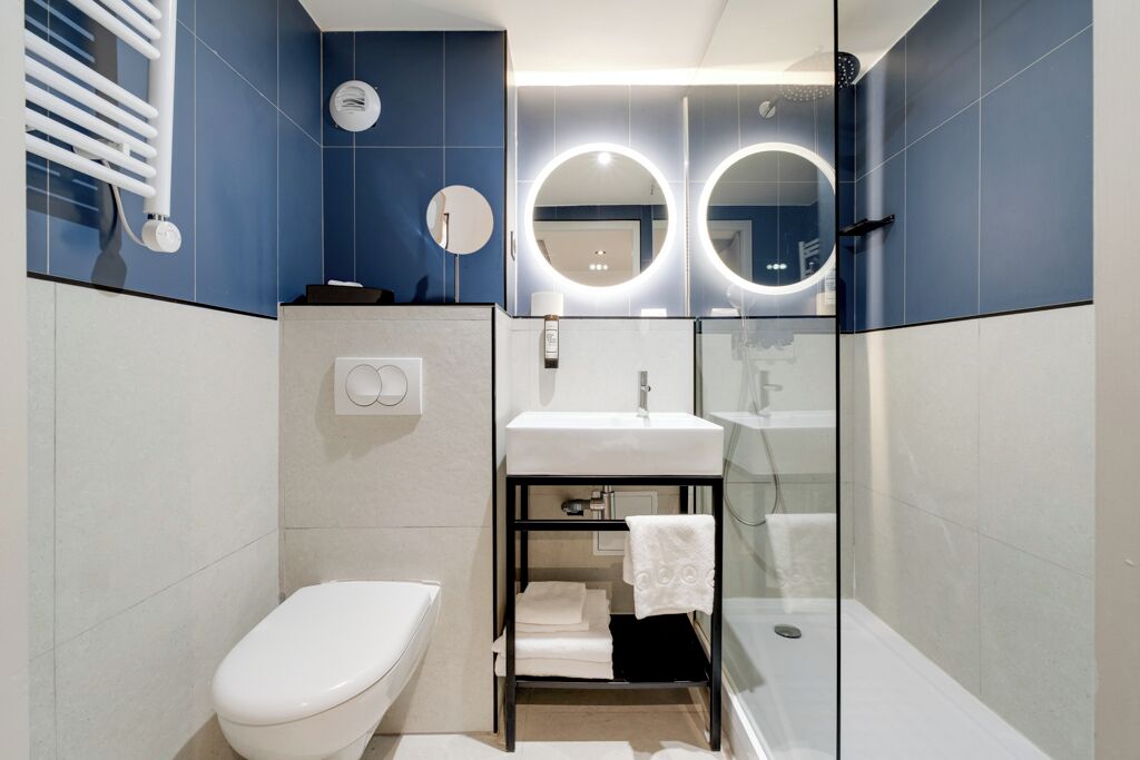 A modern bathroom with a toilet, sink, and glass shower enclosure.