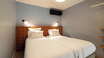 A hotel room with a double bed, two bedside tables, a wall-mounted TV, and a ceiling light.