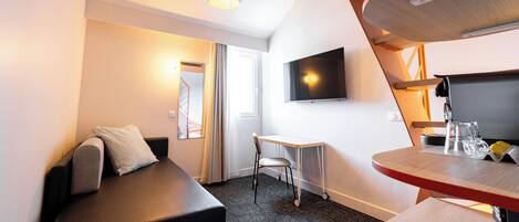 A modern hotel room with a bed, a desk, a chair, a TV, and a small table with glasses.