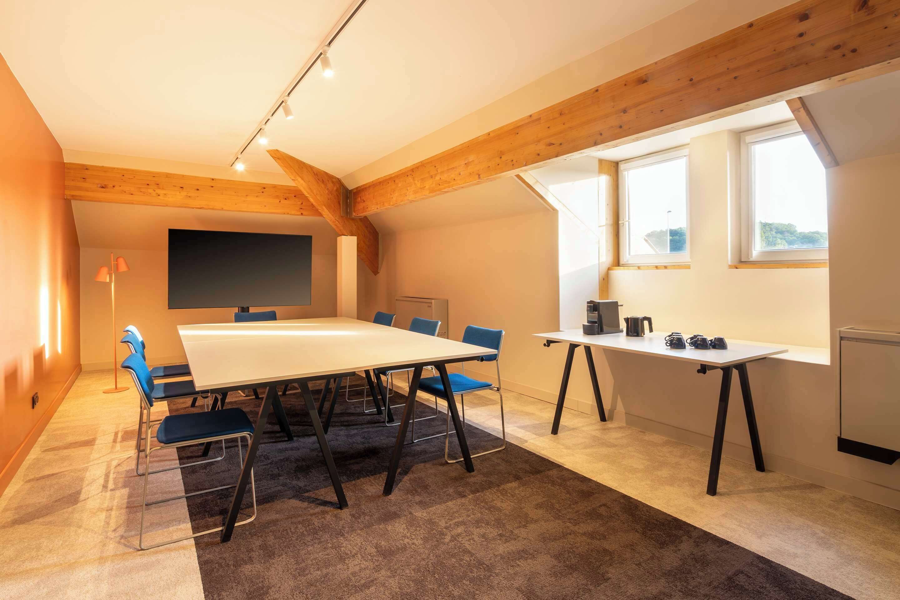 A conference room with a large table, blue chairs, a whiteboard, and a window with a view.