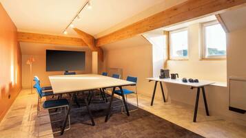 A conference room with a large table, blue chairs, a whiteboard, and a window with a view.