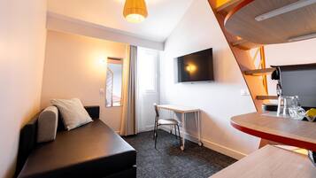 Habitación de hotel moderna con cama, escritorio, silla, televisor y una pequeña mesa con vasos.