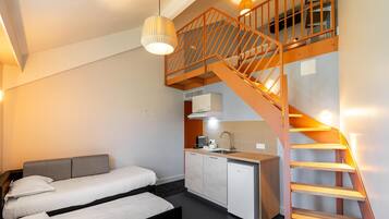 Un dormitorio con cama, kitchenette y escalera.