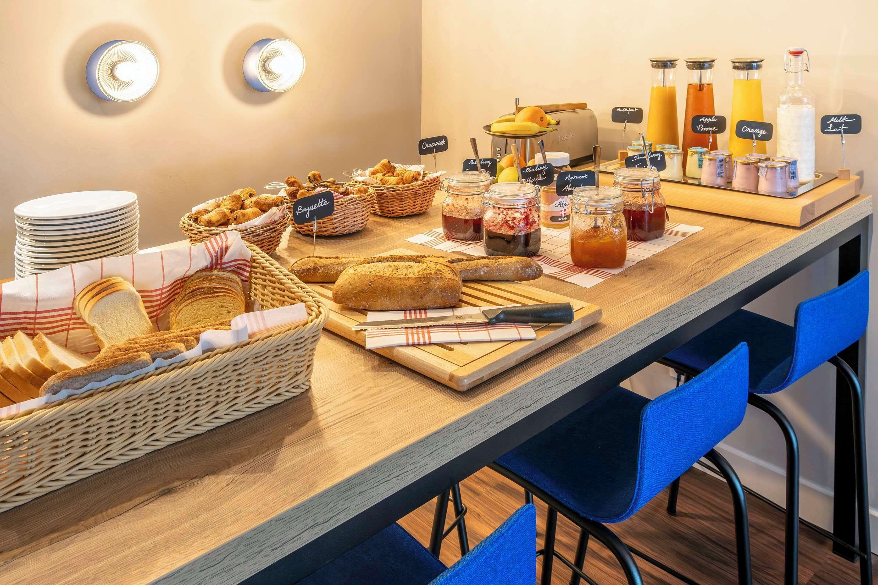 Un bufé de desayuno con pan, bollería y diversas bebidas.
