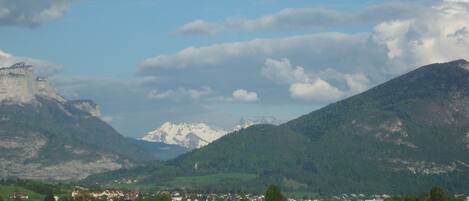 A mountainous landscape with a castle, green fields, and a small town.