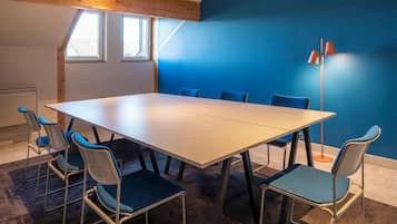 A conference room with a large table and six chairs, a floor lamp, and a blue wall.