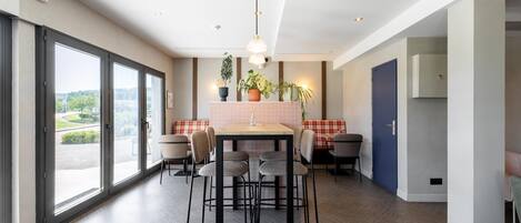 A modern kitchen with a dining area, large windows, and a view of the outdoors.
