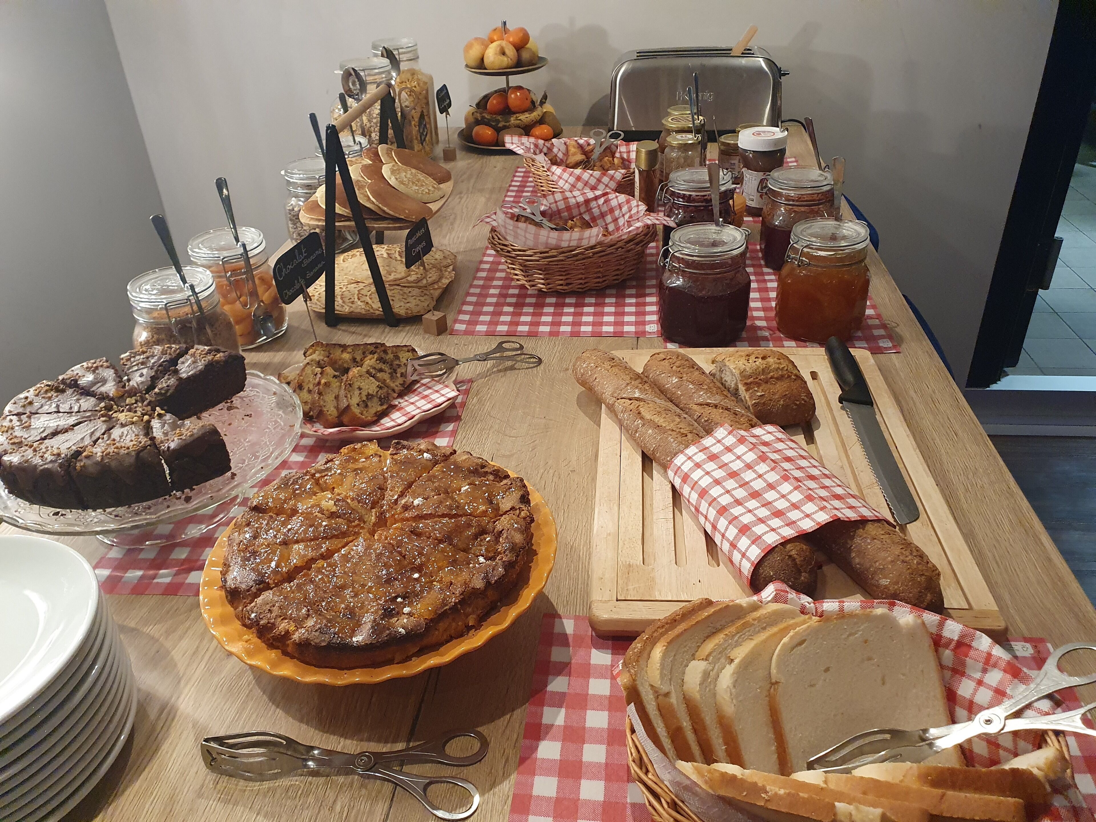 Una mesa con diversos alimentos, como un pastel, pan y frascos de conservas.