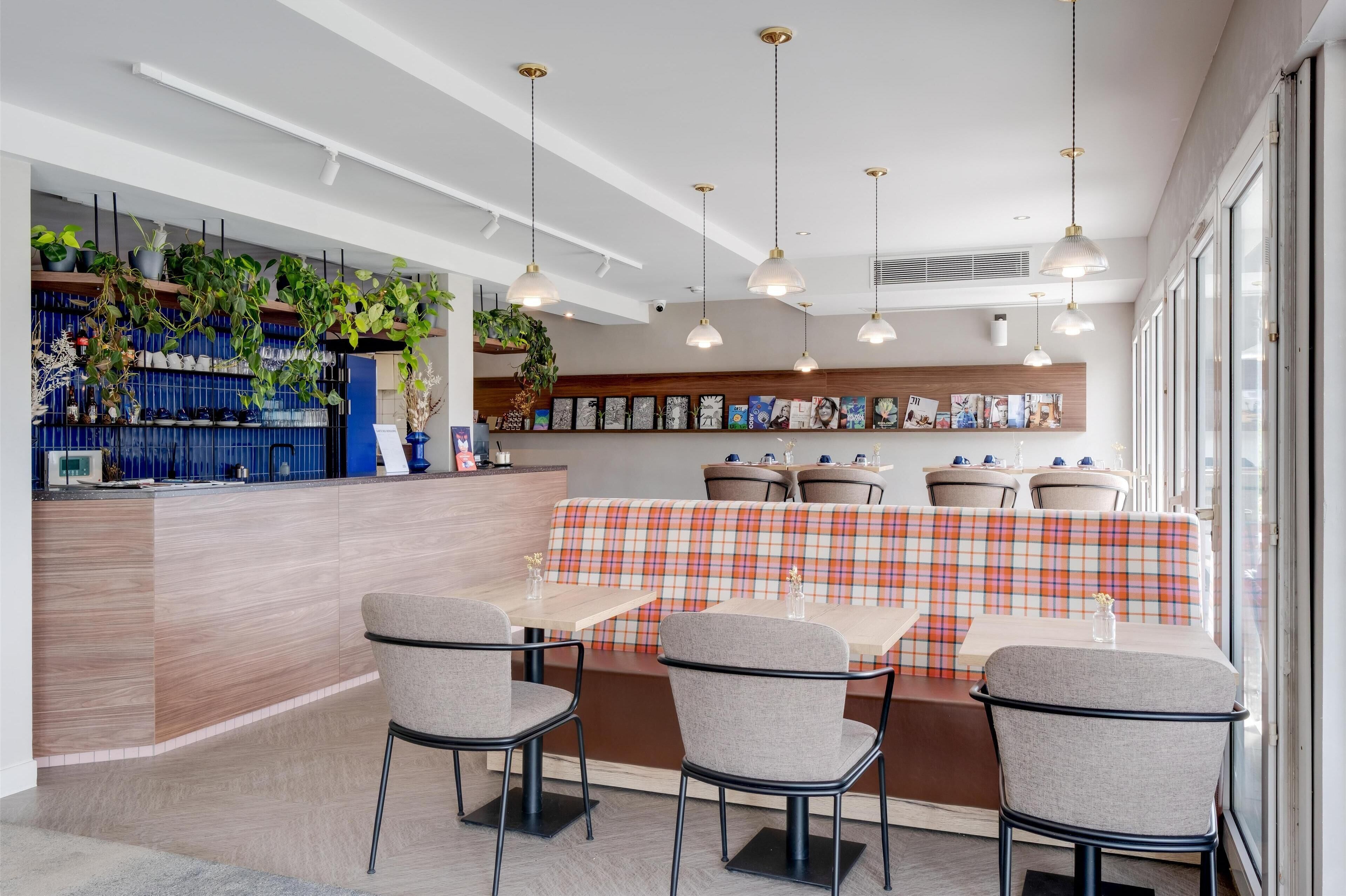 Un espace repas moderne doté d’un long comptoir, de plusieurs options d’assises, notamment un banc et des tables, et d’un éclairage suspendu.