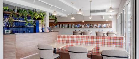 Un espace repas moderne doté d’un long comptoir, de plusieurs options d’assises, notamment un banc et des tables, et d’un éclairage suspendu.