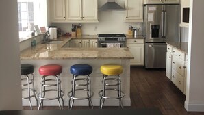 A modern kitchen with white cabinets, a stainless steel refrigerator, and a central island with stools.