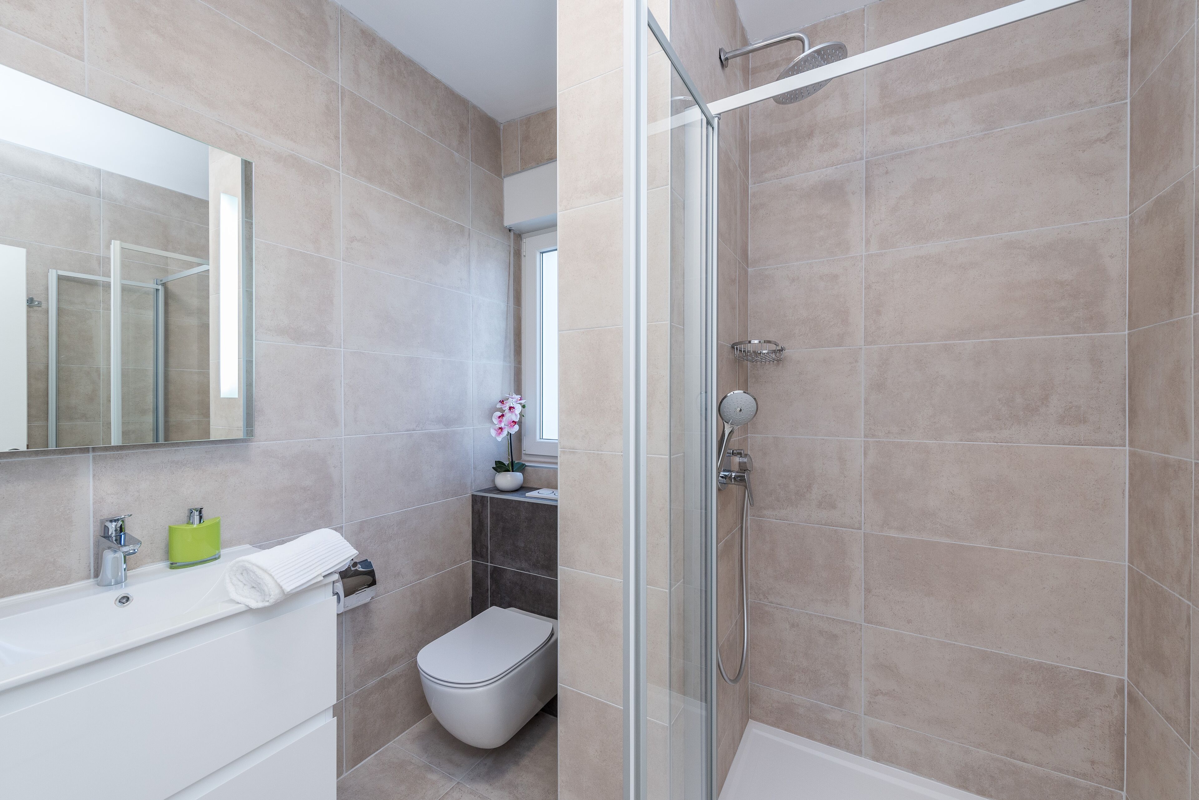 Un baño moderno con cabina de ducha de vidrio, inodoro blanco y lavabo con espejo arriba.