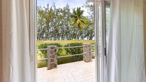 Un balcón con vista a un jardín, una palmera y árboles distantes.