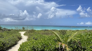A beach path leading to a turquoise sea, surrounded by lush greenery. - Stunning Luxury Villa Directly On French Leave Beach (Governors Harbour)