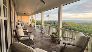 A covered porch with outdoor seating, a ceiling fan, and a view of the ocean. - Stunning Luxury Villa Directly On French Leave Beach (Governors Harbour)