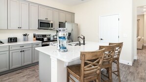 A modern kitchen with white cabinets, stainless steel appliances, and a central island with bar stools.