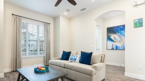 A living room with a beige sofa, a coffee table, and a ceiling fan.