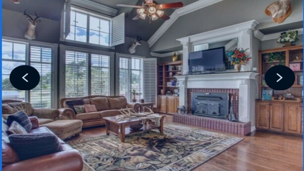 A spacious living room with a fireplace, large windows, and a ceiling fan. - A luxury hunting lodge  (Merkel)