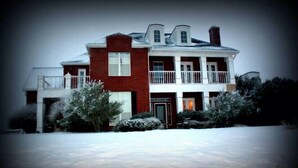 A two-story house with a balcony, a chimney, and a snow-covered driveway. - A luxury hunting lodge  (Merkel)
