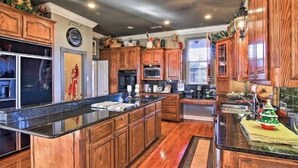 A spacious kitchen with wooden cabinets, a large island, and a built-in oven. - A luxury hunting lodge  (Merkel)