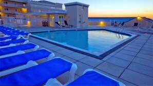 A swimming pool with blue lounge chairs and a building in the background. - 402SunsetBeach,PenthouseDir.WaterFrt,Pvt.Beach,Pool,Elev,1Blk Seacrets3BDRM/3FBH (Ocean City)