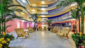 A multi-level atrium with wooden lounge chairs, potted plants, and a central seating area. - 402SunsetBeach,PenthouseDir.WaterFrt,Pvt.Beach,Pool,Elev,1Blk Seacrets3BDRM/3FBH (Ocean City)