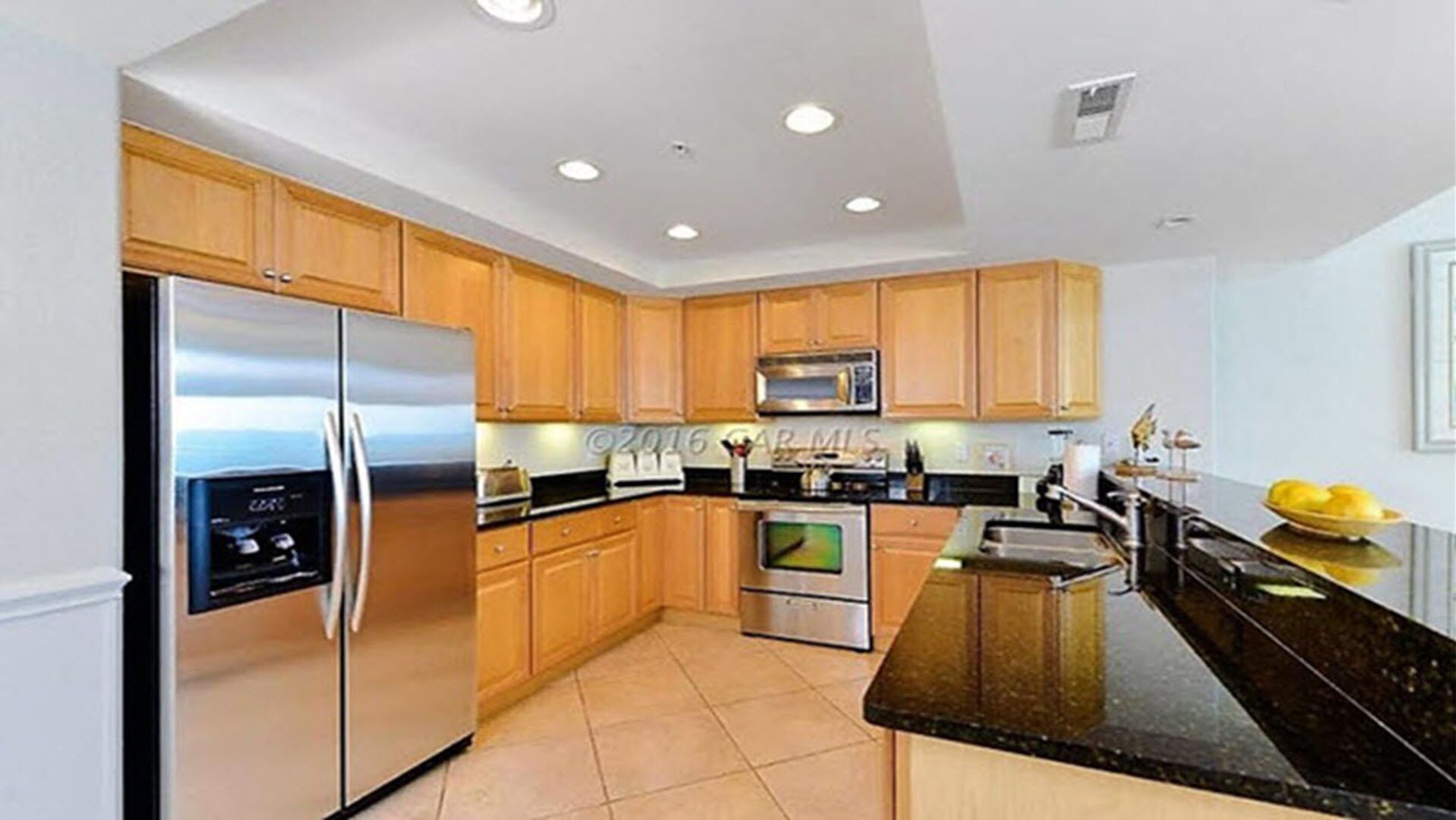 A modern kitchen with wooden cabinets, stainless steel appliances, and a black granite countertop.