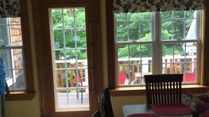 Un espace repas comprenant une table, des chaises et donnant sur une terrasse et des arbres.