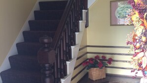Un escalier avec des marches en bois et une rampe, menant à un palier où se trouvent un panier et des fleurs.
