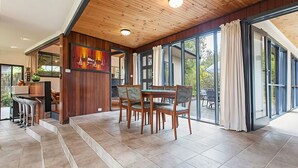 A spacious room with a wooden ceiling, a dining area with a table and chairs, and large sliding glass doors leading to an outdoor patio. - Tranquil Oasis - Pet friendly (BALNARRING BEACH)