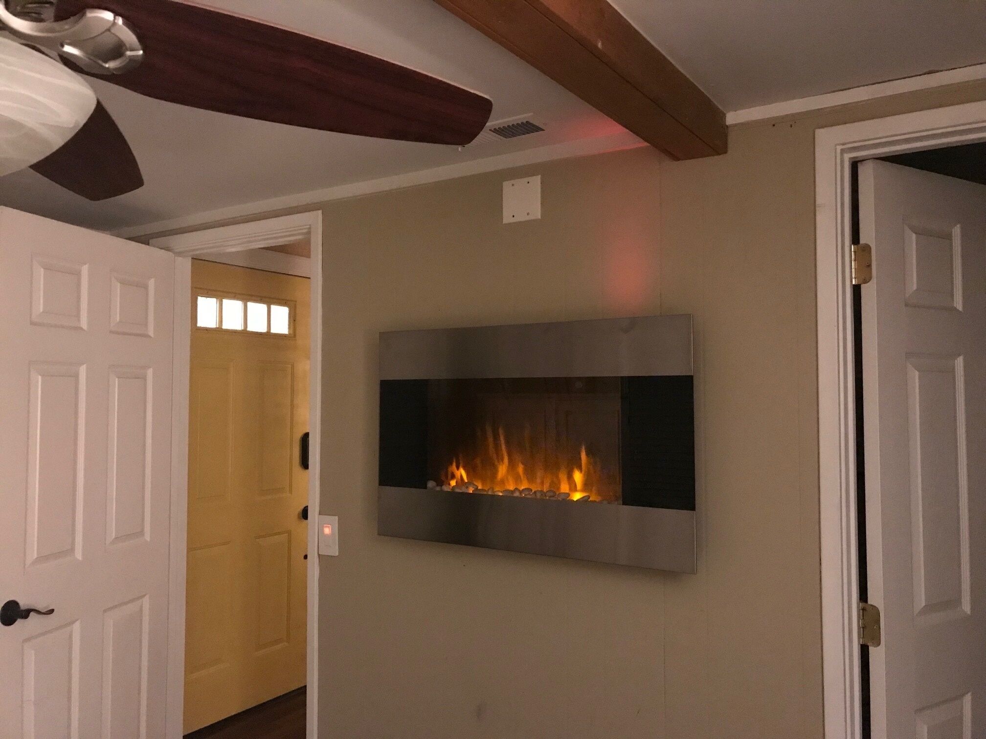 A room with a fireplace, white doors, and a ceiling fan.