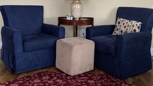 A living room with two blue armchairs, a small beige ottoman, a table with a lamp, and a framed picture on the wall. - Brigantine~2blks to beach~2bdr~1bth~front porch~bck deck~fencedyard ~allow dogs (Brigantine)