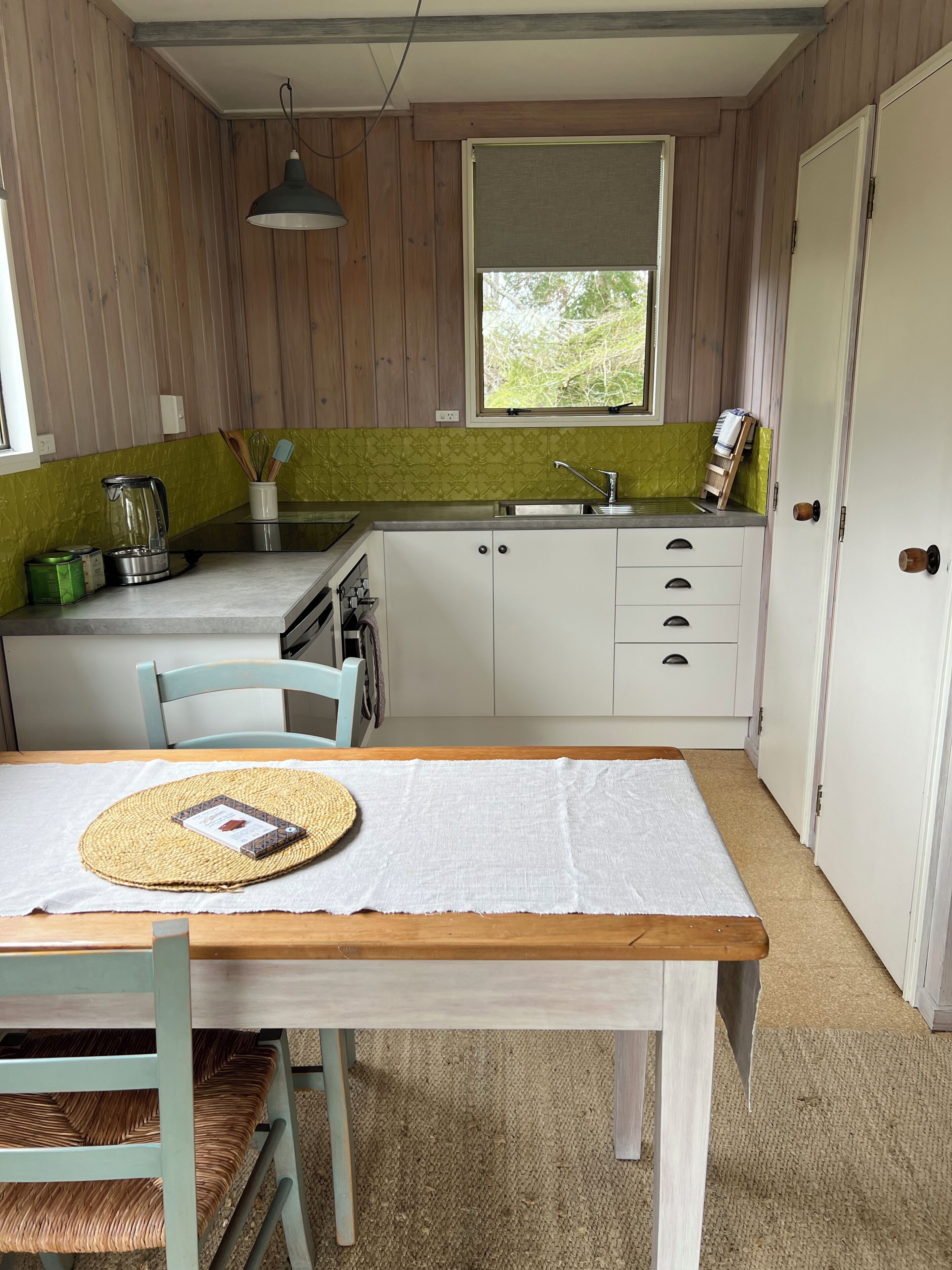 A compact kitchen with a window, a sink, and a dining area with a table and chairs.