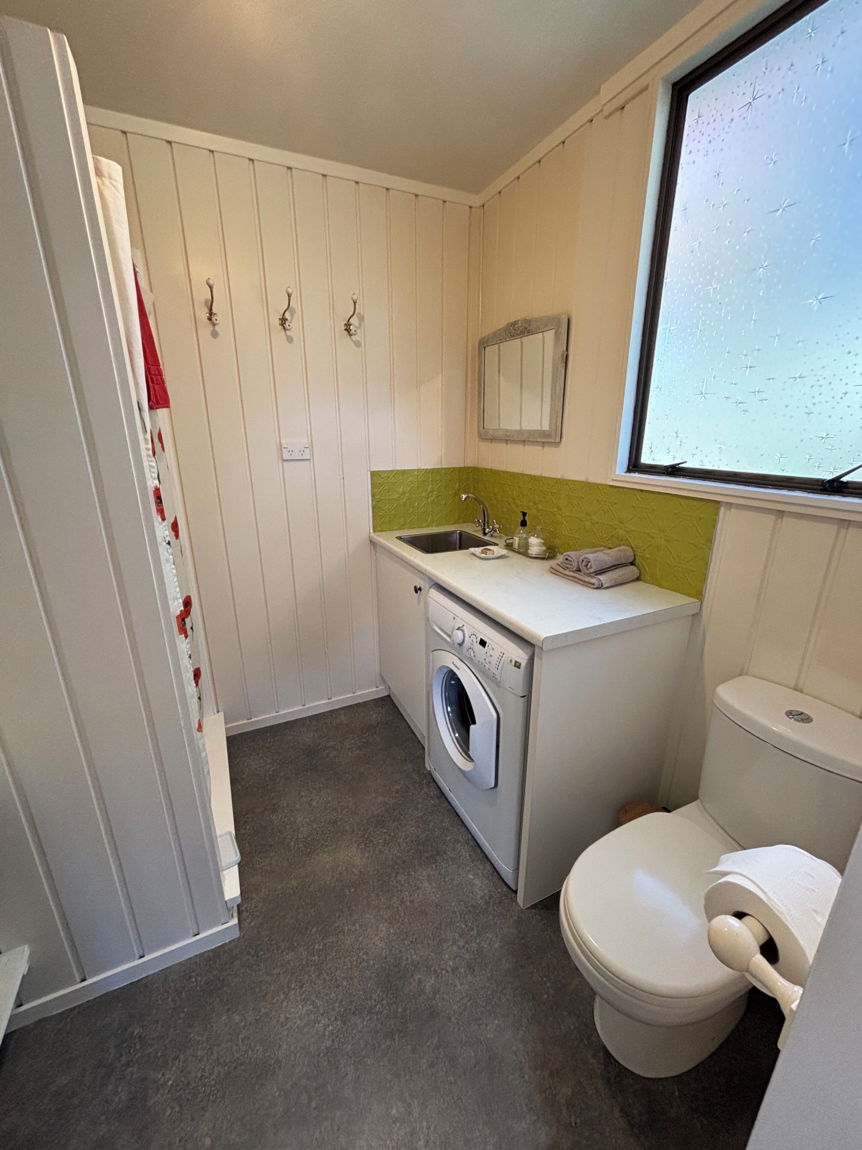 A compact bathroom with a washing machine, sink, and toilet.