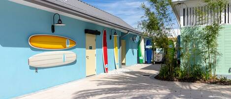 A pathway lined with surfboards on a building's exterior wall, leading to a door.
